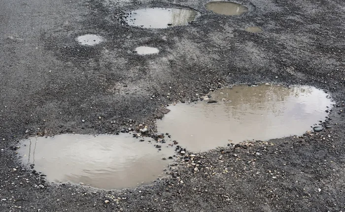 Puddles standing in a potholed parking lot